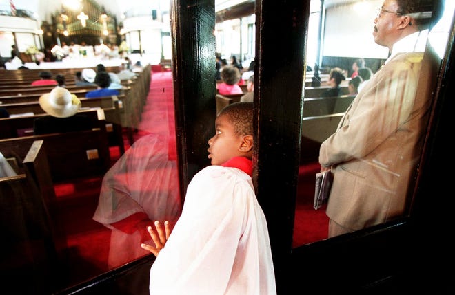 Alcoylite Kyle Jones peaks in during services Sunday morning, Aug. 12, 2001, at Evans Metropolitan AME Zion Church.