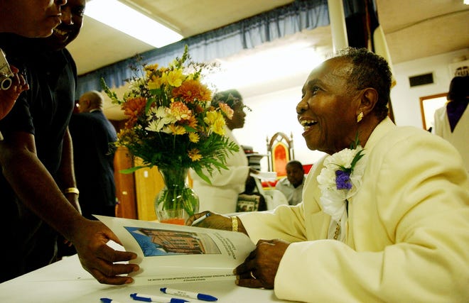 Annette Billie signs copy of her book which chronicles the 210 year history of the Evans Metropolitan AME Zion Church in Fayetteville in 2006.