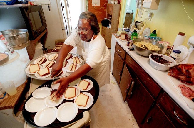 Mary Lewis cuts up the cake and puts it on plates for dessert at the supper at Mt. Sinai Baptist Church, Sunday, Aug. 19, 2001.