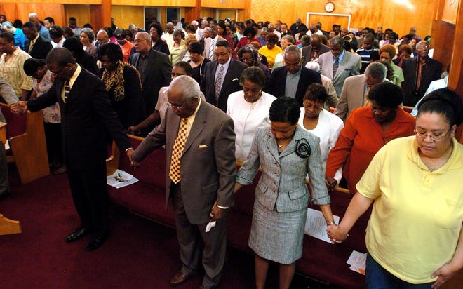 A full house holds hands and bows their heads in prayer during a rally to support E.E. Smith High School at Mount Sinai Baptist Church on March 12, 2006.