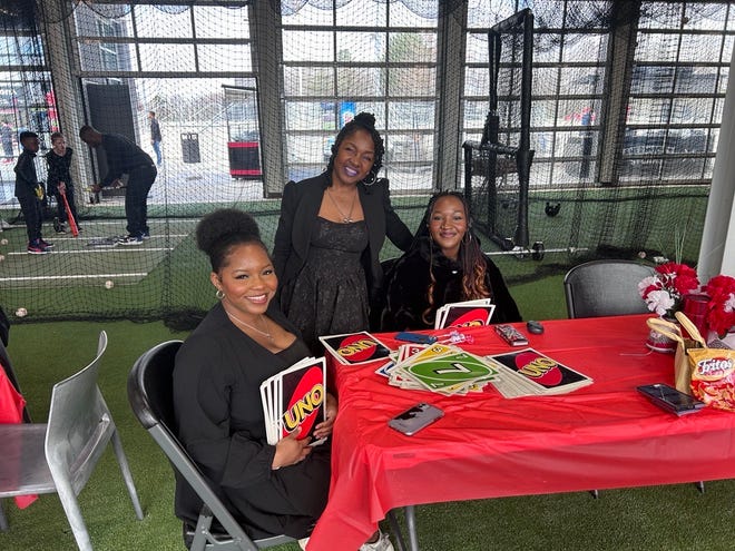 From left: Savanna Blanton, 25, Stephanie Brown, 54, and Gabrielle White, 16, playing Uno at the 3rd annual It's a Family Affair Sneaker Ball event at Segra Stadium, Mar. 2, 2024.