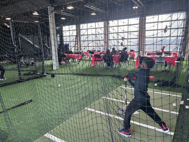 8-year-old Aidan Taylor practicing his baseball swing with father, Shed Taylor, 42, at the 3rd annual It's a Family Affair Sneaker Ball event at Segra Stadium, Mar. 2, 2024.