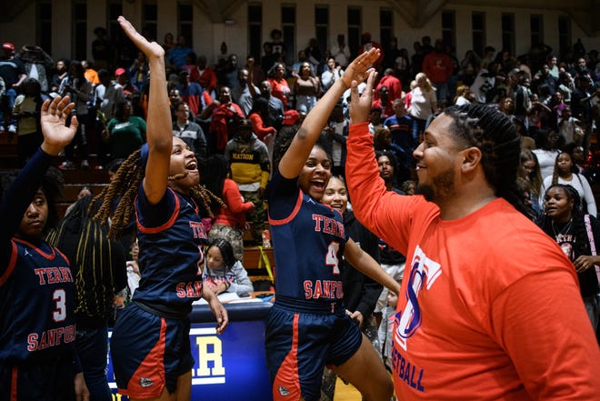 Terry Sanford head coach Christopher Goodman gets high fives Jaidiah Blake, left to right, Breonna Roaf and Zaniya Reddick after defeating Cape Fear in the fourth round of 3A East playoff game on Friday, March 8, 2024.