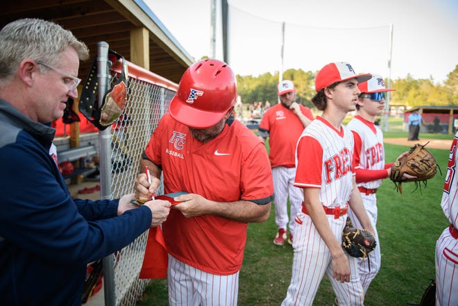 Freedom Christian Academy head coach Shaun Stafford signs the ribbon they cut moments earlier at the school’s new baseball field during a game against St. Pauls on Thursday, March 14, 2024.