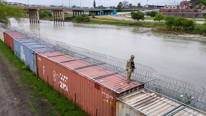 March 17, 2024: In an aerial view, a Texas National Guard soldier stands atop a barrier of shipping containers and razor wire while guarding the U.S.-Mexico border in Eagle Pass, Texas. Texas National Guard troops have fortified the U.S.-Mexico border with a vast amount of razor wire as part of Governor Greg Abbott's "Operation Lone Star" to deter migrants from crossing into Texas. The U.S. southwestern border stretches nearly 2,000 miles, from the Gulf of Mexico to the Pacific Ocean, and is marked by fences, deserts, mountains, and the Rio Grande, which runs the entire length of Texas. The politics surrounding border and immigration issues have become dominant themes in the U.S. presidential election campaign.