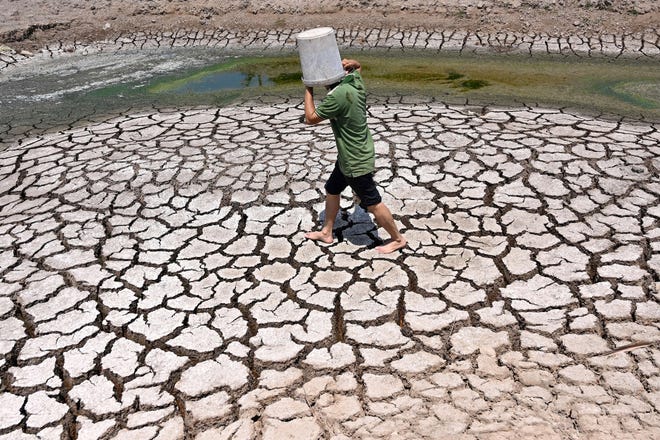 March 19, 2024: A man carries a plastic bucket across the cracked bed of a dried-up pond in Vietnam's southern Ben Tre province. Every day, farmer Nguyen Hoai Thuong prays in vain for rain to fall on the cracked, dry earth of her garden in Vietnam's Mekong Delta -- the country's "rice bowl" agricultural heartland. A blazing month-long heatwave has brought drought, parching the land in Thuong's home of Ben Tre province, 130 kilometers (80 miles) south of business hub Ho Chi Minh City.